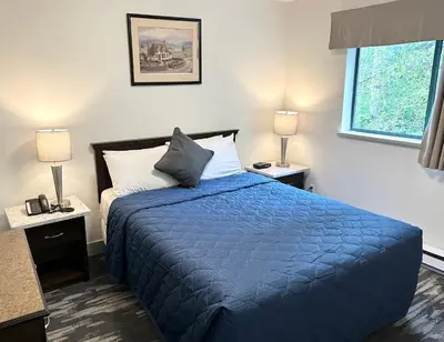 a bedroom with a bed with a blue comforter and two lamps at Canadian Inn in Surrey