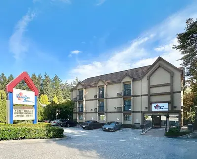a large building with cars parked in a parking lot at Canadian Inn in Surrey