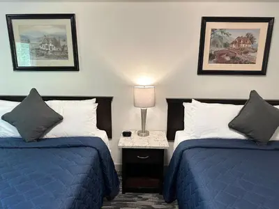 a hotel room with two beds and a table with a lamp at Canadian Inn in Surrey