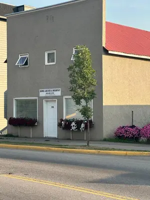 a gray building with flower boxes and a white door at Burns Lake Bed and Breakfast in Burns Lake