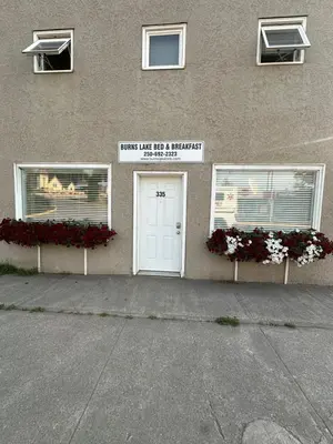 a building with a white door and two windows at Burns Lake Bed and Breakfast in Burns Lake