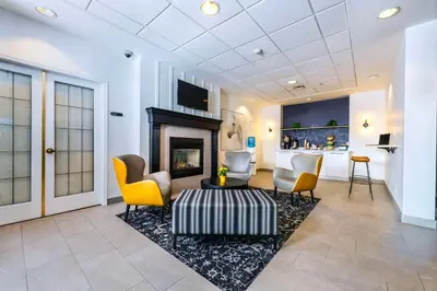 a living room with a fireplace and yellow chairs at Clarion Hotel & Conference Centre in Abbotsford