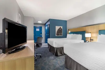 a hotel room with two beds and a flat screen tv at Clarion Hotel & Conference Centre in Abbotsford