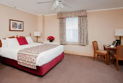 a bedroom with a bed and a desk and a window at Harrison Hot Springs Resort & Spa in Harrison Hot Springs