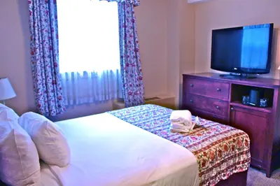 a bedroom with a bed with a television and a dresser at Harrison Hot Springs Resort & Spa in Harrison Hot Springs