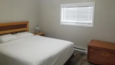 a bedroom with a white bed and a window at Sandy Beach Suites in Osoyoos