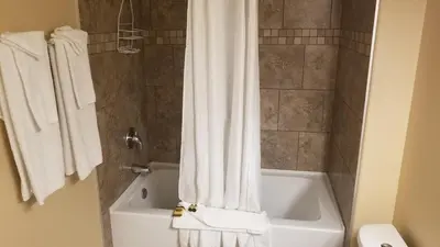 a bathroom with a white shower curtain next to a tub at Sandy Beach Suites in Osoyoos