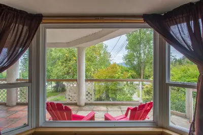 a screened in porch with red chairs in front of a window at Higgin's Inn in Powell River