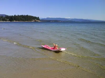 a girl is laying on a pink raft in the water at Higgin's Inn in Powell River