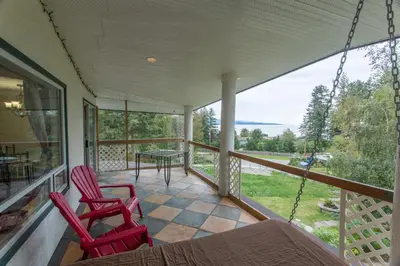 a porch with two red chairs and a table at Higgin's Inn in Powell River
