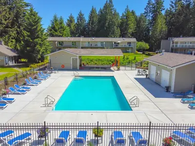 an overhead view of a swimming pool with blue chairs at Ocean Trails Resort in Parksville