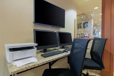a desk with three computer monitors and a printer at Best Western PLUS Chemainus Inn in Chemainus