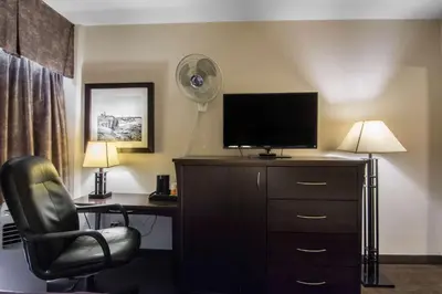 a hotel room with a desk and a chair and a fan at Quality Inn & Suites Yellowknife in Yellowknife
