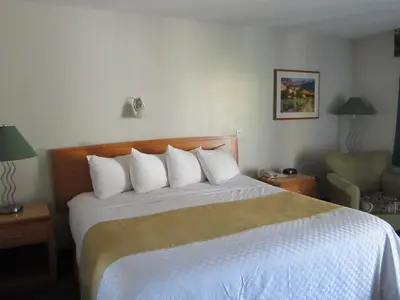 a hotel room with a bed with white sheets and pillows at Ramada Merritt in Merritt