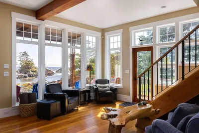 a living room with large windows and a staircase at Black Rock Beach House in Ucluelet