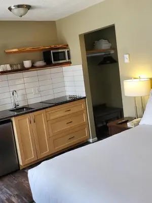 a room with a bed and a kitchen with a microwave at Alpine Inn & Suites in Nelson