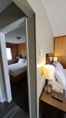 a hotel room with a bed and a desk with a lamp at Alpine Inn & Suites in Nelson