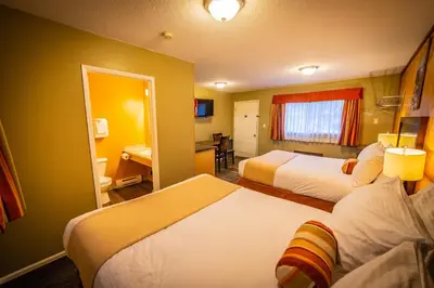 a hotel room with two beds and a desk at Alpine Inn & Suites in Nelson
