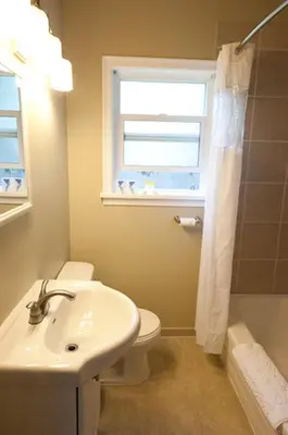 a bathroom with a sink and a toilet and a window at Alpine Inn & Suites in Nelson
