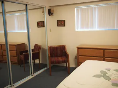 a bedroom with a bed and a desk and a chair at Whale's Tail Guest Suites in Ucluelet