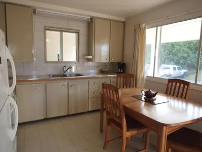 a kitchen with a wooden table and a dining room at Whale's Tail Guest Suites in Ucluelet