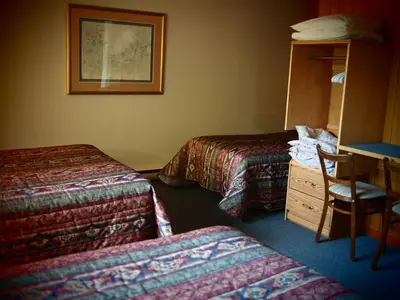 a hotel room with two beds and a desk at Whale's Tail Guest Suites in Ucluelet