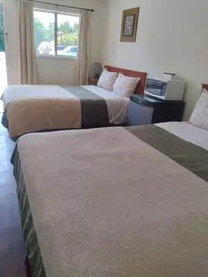 a hotel room with two beds and a window at Dolphin Motel in Tofino