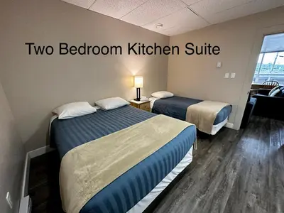 two beds in a room with two bedroom kitchen suite at West Coast Motel on the Harbour in Ucluelet