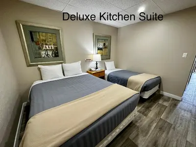 two beds in a hotel room with the words deliver kitchen suite at West Coast Motel on the Harbour in Ucluelet