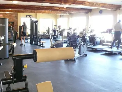 a gym with cardio equipment and people in the background at West Coast Motel on the Harbour in Ucluelet
