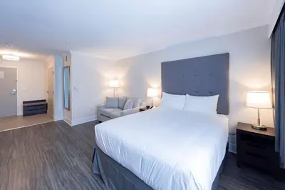 a bedroom with a large white bed and a chair at Prestige Treasure Cove Resort in Prince George