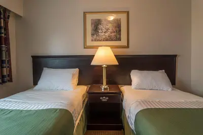 a hotel room with two beds and a lamp at Port Augusta Inn in Comox