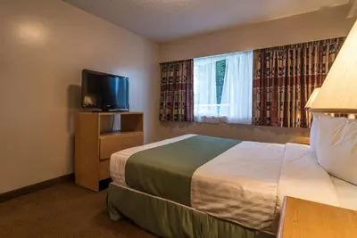 a hotel room with a bed and a flat screen tv at Port Augusta Inn in Comox