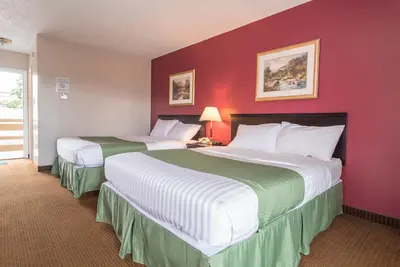 two beds in a hotel room with red walls at Port Augusta Inn in Comox