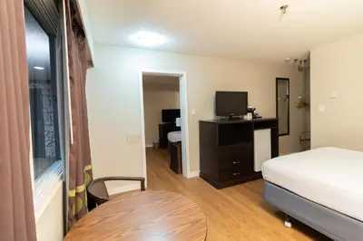 a bedroom with a bed and a table and a television at Super 8 by Wyndham Prince George in Prince George