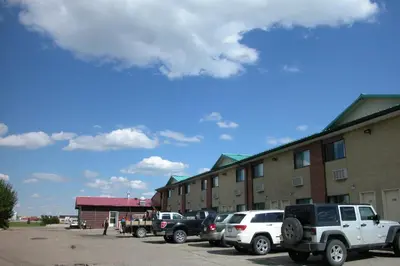 a parking lot with cars parked in front of a building at Best Seven Inn in Claresholm
