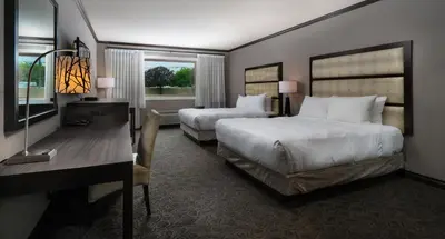 a hotel room with two beds and a desk at Prestige Vernon Hotel in Vernon