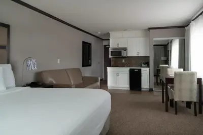 a hotel room with a bed and a kitchen at Prestige Vernon Hotel in Vernon