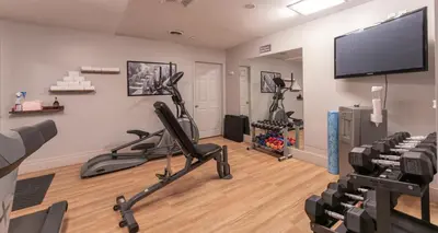 a room with a gym with exercise equipment and a flat screen tv at Prestige Golden Hotel in Golden