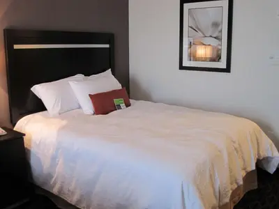 a bedroom with a white bed with a book on it at Hampton Inn by Hilton Fort Saskatchewan in Fort Saskatchewan
