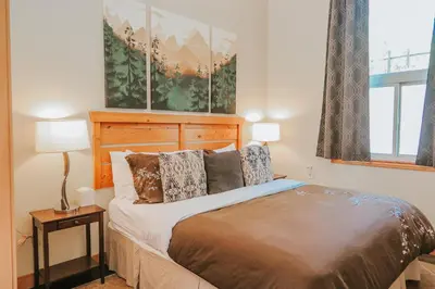 a bedroom with a bed with a wooden headboard at Cobble Wood and Bird Sanctuary Guest Houses in Tofino
