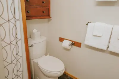 a bathroom with a white toilet and towels at Cobble Wood and Bird Sanctuary Guest Houses in Tofino