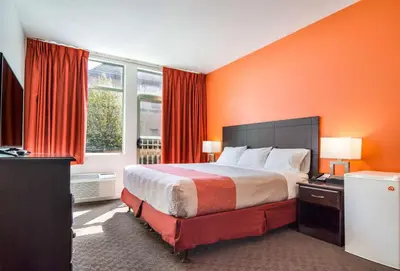 a hotel room with a bed with orange walls at Motel 6 Surrey, Bc in Surrey