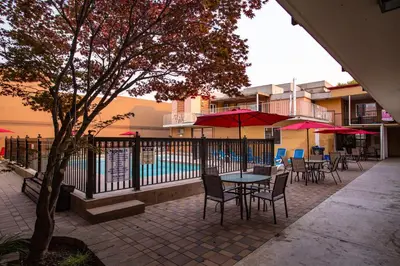 a patio with tables and chairs with umbrellas and a pool at Sahara Courtyard Inn Penticton in Penticton