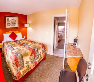 a hotel room with a bed and a corridor at Sahara Courtyard Inn Penticton in Penticton