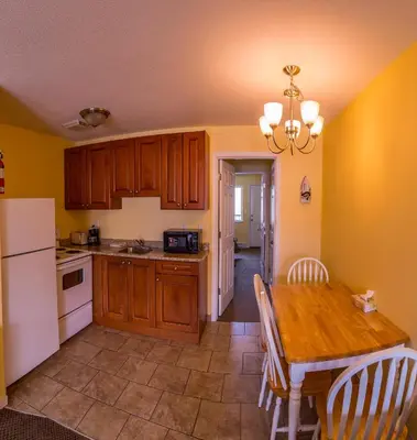 a kitchen with a wooden table and a white refrigerator at Sahara Courtyard Inn Penticton in Penticton