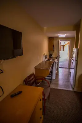 a room with a kitchen with a table and a television at Sahara Courtyard Inn Penticton in Penticton