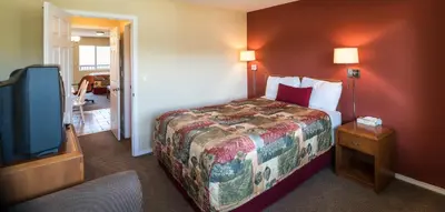 a hotel room with a bed and a flat screen tv at Sahara Courtyard Inn Penticton in Penticton