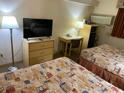 a hotel room with two beds and a flat screen tv at Lone Star Hotel in North Battleford