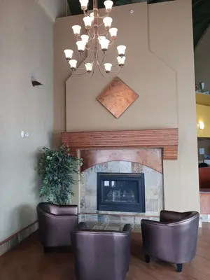 a living room with a fireplace and two leather chairs at Lakeview Inns & Suites - Hinton in Hinton